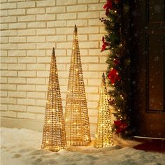 three small christmas trees in front of a brick wall