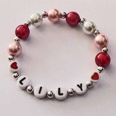 a beaded bracelet with the word july written on it and red, white and silver beads