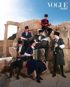 a group of men sitting on top of a rock formation with an accordion in front of them