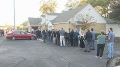 a group of people standing in front of a house talking to each other on the street