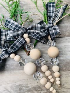 an assortment of beads and bows on a wooden surface with greenery in the background