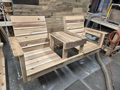 a wooden bench and table sitting next to each other in front of a pile of wood planks