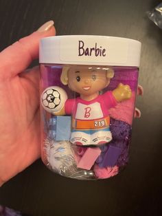 a hand holding a jar filled with toys