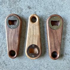 three wooden bottle openers sitting next to each other on a cement surface with one open and the other closed