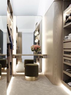 a walk - in closet with two stools and a mirror on the wall next to it