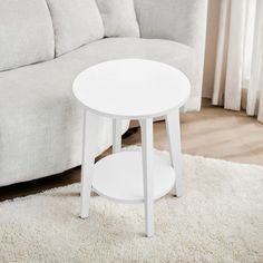 a white coffee table sitting on top of a rug in front of a gray couch