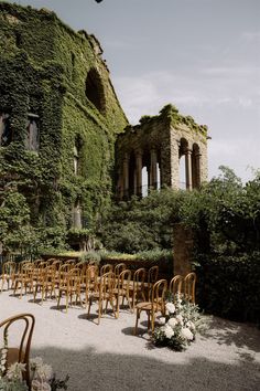 rows of wooden chairs sitting in front of an old building with ivy growing on it