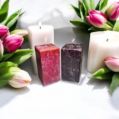 three candles sitting next to each other with tulips in the background