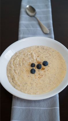 a white bowl filled with oatmeal and blueberries on top of a table