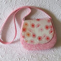 a pink and white purse sitting on top of a bed