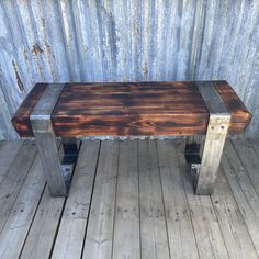 a wooden bench sitting on top of a wooden floor next to a metal pole wall