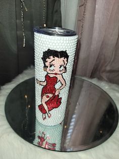 a glass with a cartoon character on it sitting on a table next to a curtain