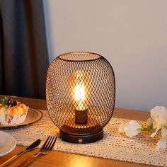 a table topped with plates and a lit candle on top of a wooden tablecloth