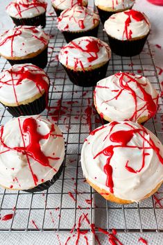 cupcakes with white frosting and red sprinkles on a cooling rack