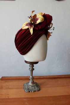 **Made to order** Mascherina for Feral Vintage. This a collaboration between my two stores. Add some glamour to your work from home look, or stun everyone on your next zoom pub quiz. Feel fabulous in this vintage reproduction headpiece 1940's style wine red velvet turban. This turban is a full covering style knotting at the front with a large knot embellishment in the front. Gold and burgundy glittered stargazer lilies decorate the knot The turban pulls on, no fastenings or tying knots and it si 1940s Pinup, 1940's Style, Velvet Turban, Rockabilly Girl, Carmen Miranda, Modern Pin Up, Pin Up Models, Stargazer Lily, Rockabilly Style