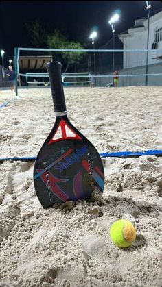 a tennis racket and ball in the sand