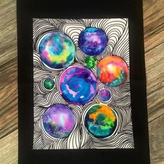 an art project with watercolors and black paper on a wooden surface, depicting different colors