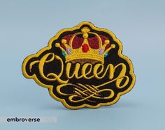 an embroidered patch with the word queen written in cursive writing and a crown