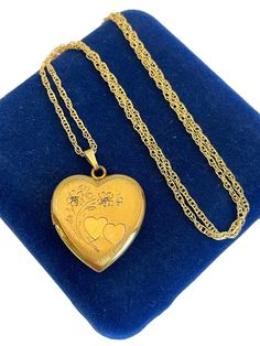 Description: Beautiful heart shaped 12K gold filled locket necklace with etched overlapping double hearts with flowers and leaves above them on the front side. This Retro Era pendant locket is plain with no design on the back.. The bale is an elongated triangular shape with vertical lines in the shape of a "V".  The front and the back of this locket have a shiny finish. This vintage locket has places for two portraits inside.  One of the original frames remains. The hinge is on the left side and this locket opens from the right. The locket opens and closes securely with a snap. It is attached to a new, 20''' long 14K gold filled rope chain, which has a lobster clasp. The clasp opens and closes securely.  Measurements: Locket: Approximately 1" long, approx. 7/8'' wide Gold filled Chain: 20" Vintage Locket, Pendant Locket, Retro Era, Vintage Lockets, Vertical Lines, Double Heart, Heart Locket, Beautiful Heart, Flower Heart