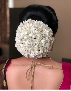 the back of a woman's head with white flowers on her neck and shoulders