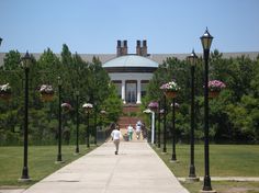 two people walking down a sidewalk in front of a large building with columns and lights