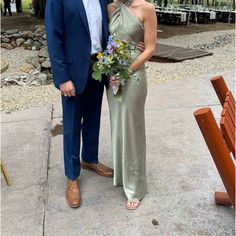 a man and woman standing next to each other in front of a bench with flowers on it