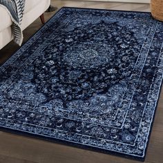 a blue area rug with an ornate design on the center and bottom, in front of a white couch