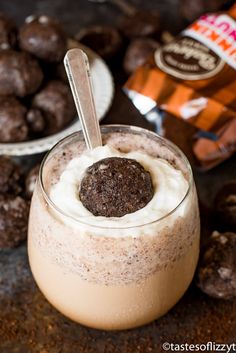 a dessert in a glass with a spoon and chocolate cookies on the side next to it