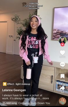 a woman standing in front of a tv holding a pink cup and smiling at the camera