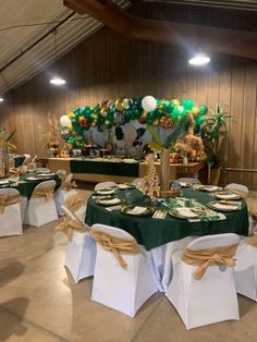 tables set up with green and white linens for a banquet or wedding reception in a barn