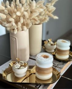 two vases filled with flowers on top of a gold tray next to other containers