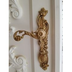 an ornate gold door handle on a white door