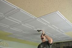 a man is painting the ceiling in his living room