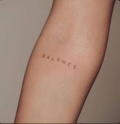 a woman's arm with the word balance tattooed on her left side, in cursive font