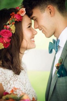 a man and woman with flowers in their hair looking at each other while smiling for the camera