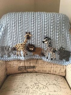 a crocheted baby's blanket with animals and zebras on it is sitting in a chair