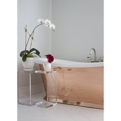 a bathroom with a bathtub and flowers on the side table in front of it