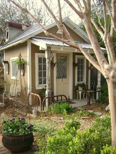 a small house sitting in the middle of a yard with lots of plants and flowers