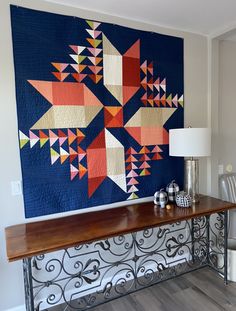 a large quilt hanging on the wall next to a table