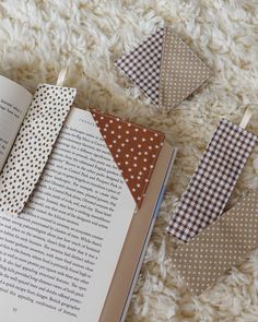 an open book sitting on top of a white carpet next to some folded paper triangles