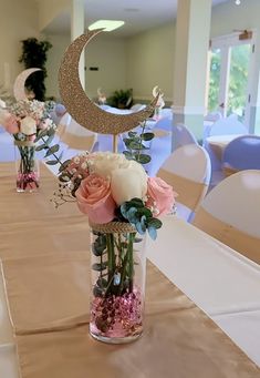 there are flowers in vases on the table at this wedding reception, and one is decorated with a half moon