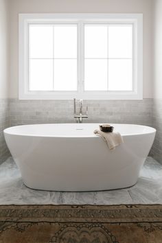 a large white bath tub sitting under two windows