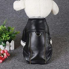 a stuffed animal in a black leather purse next to flowers and a white planter