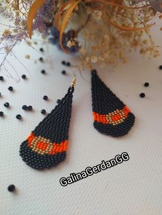 two black and orange beaded earrings sitting on top of a table next to flowers