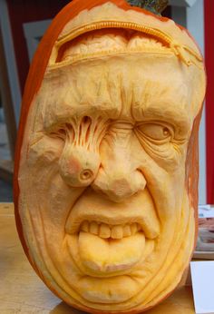 a pumpkin carved to look like an angry man's head with his mouth open