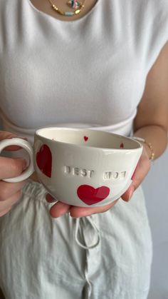 a woman holding a white bowl with red hearts on it and the words i love you