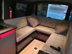 the inside of a camper with couches and pillows on it's side