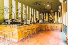 the interior of a restaurant with tables and stools lined up against the bar area