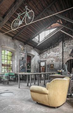 a bike hanging from the ceiling in a room with tables, chairs and other furniture