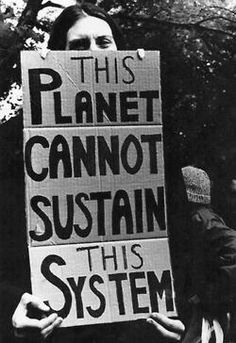 two people holding signs that read this planet cannot not suttain this system